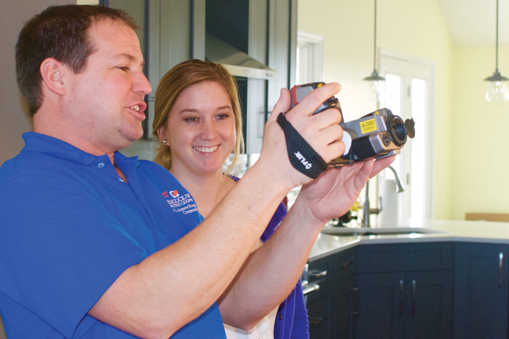 Bruce Warnecke, energy services advisor at Hancock-Wood Electric Cooperative, shows Leslie Guisinger, the cooperative’s communications coordinator, how an infrared camera can identify air leaks.